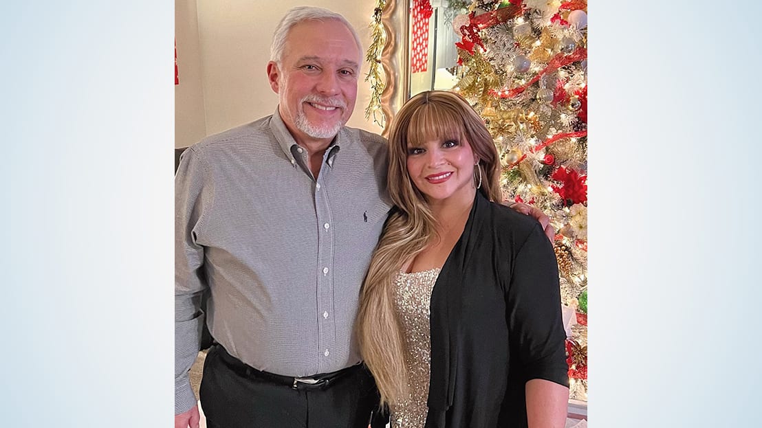 Man and woman pose in front of a Christmas tree