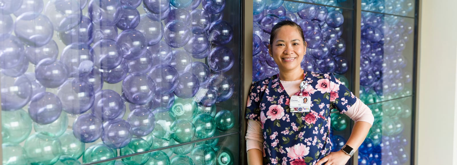 Mary Bridge RN Precious stands in front of the glass float wall.