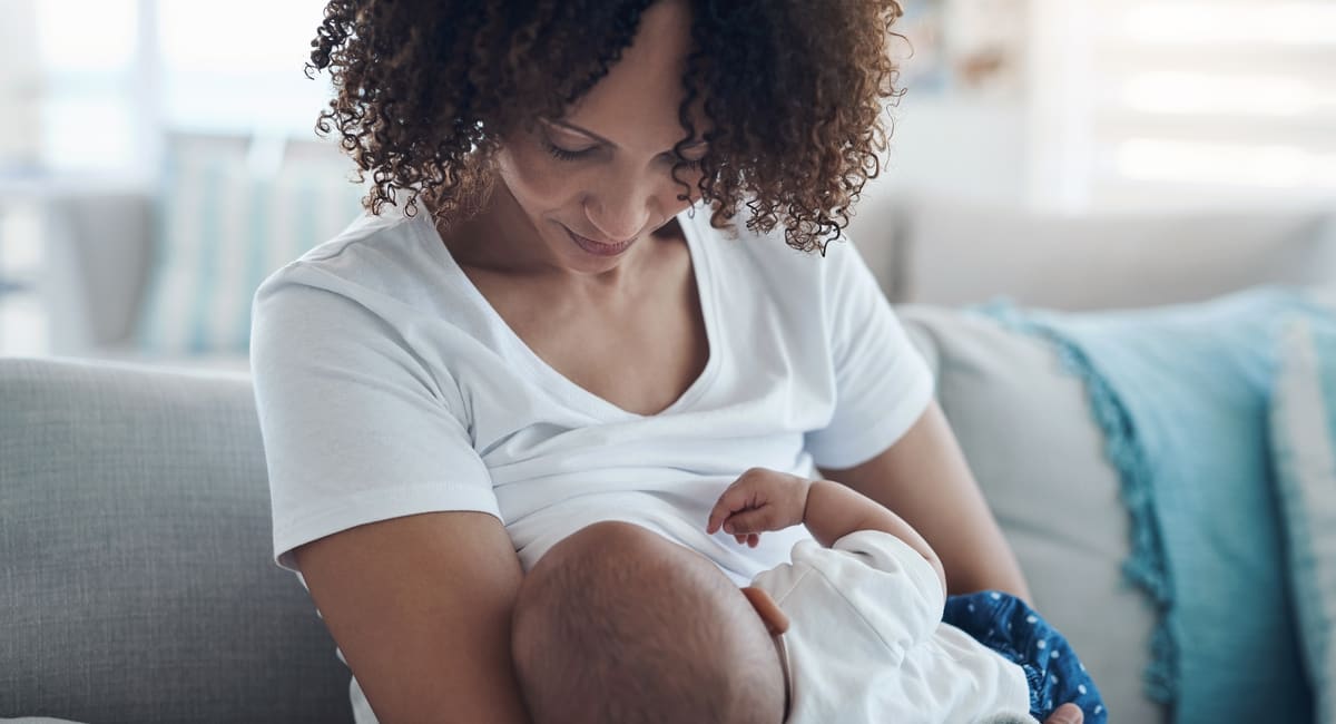 Women with dark curly hair breastfeeding an infant