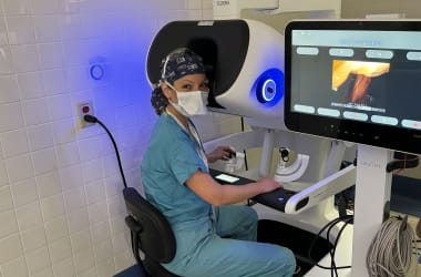 Surgeon sitting at the console of a surgical robot during a patient procedure