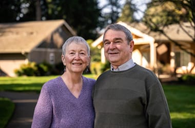 Woman and man pose for a portrait in a sunny backyard