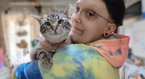 Picture of a young person in a tie-dyed sweatshirt holding a cat