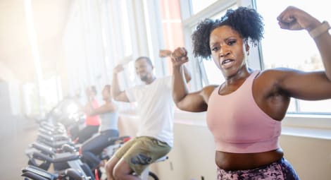 Woman on an exercise bicycle flexing her biceps