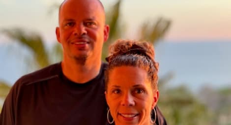 Man and woman with palm trees blurred in background