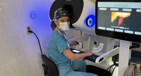 Surgeon sitting at the console of a surgical robot during a patient procedure