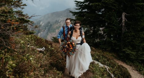 Man and woman in wedding clothes hiking.