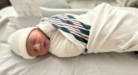 Newborn baby swaddled in hospital blanket.