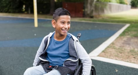 Smiling boy sitting in wheelchair at a park