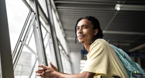 Young adult male wearing a backpack gazing out a window