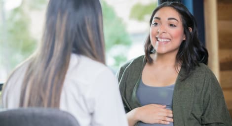 Young adult Hispanic expectant mother is discussing her pregnancy with a midwife during a support group meeting or childbirth class.