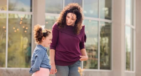 Mother and daughter smiling in front of school