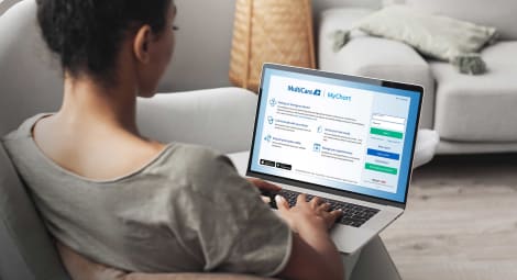 Woman using laptop computer on sofa, logging into her MyChart account.