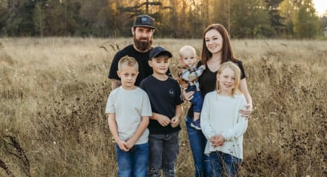 Family portrait of dad, mom, three boys and a girl in a field with tall grass