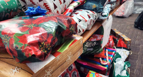 Piles of Christmas gifts stacked on a table in a conference room