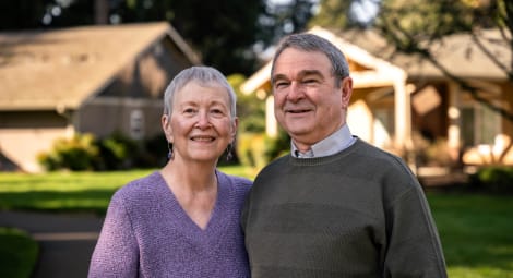 Woman and man pose for a portrait in a sunny backyard