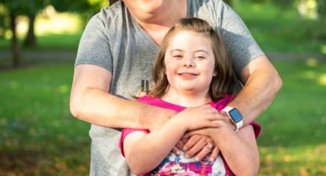 Mother and daughter hugging and smiling at the camera