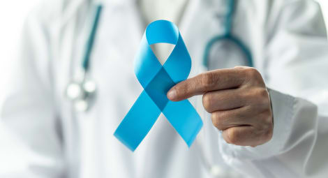 Man with stethoscope holding a blue ribbon.