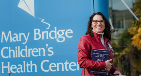 Dr. Ladish smiling in front of a sign