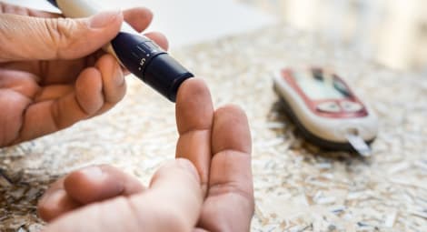 Finger being pricked by a diabetes needle