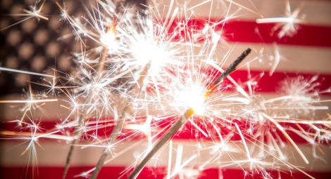 Lit sparklers held in front of the U.S. flag