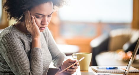 Young woman with a concerned expression reading a text on her phone