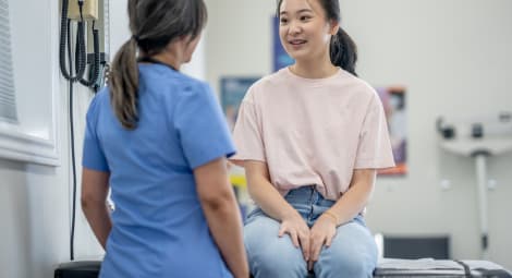 Young girl sits on exam table and talks with provider