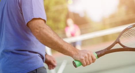 Close-up of man’s arm holding tennis racket