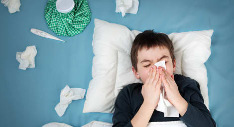 Boy blowing his nose in bed