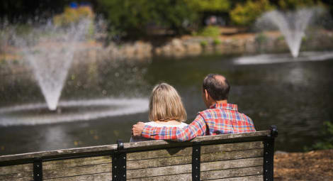 Older couple sitting on bench looking at a fountain