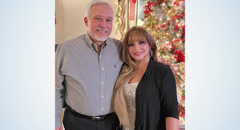 Man and woman pose in front of a Christmas tree