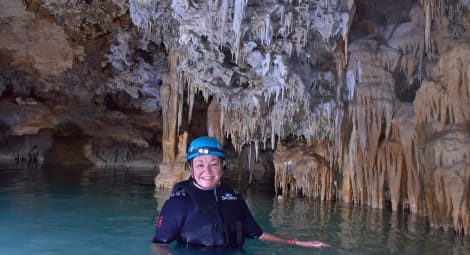 Woman standing in side of a cave filled with water.