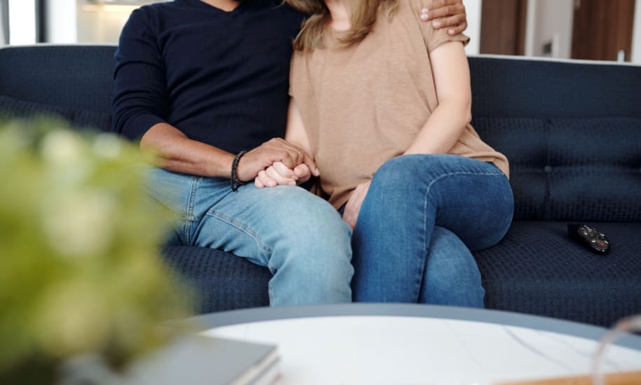 A man and a woman sitting on a blue couch holding hands