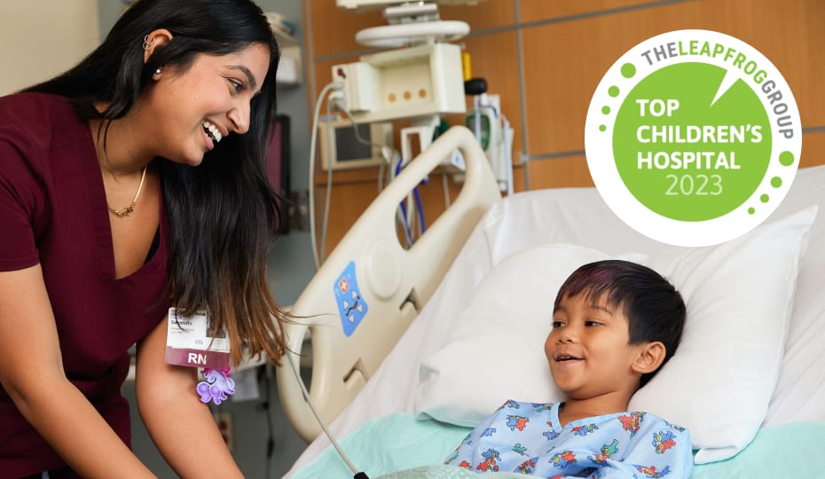 Nurse smiles at young boy in hospital bed