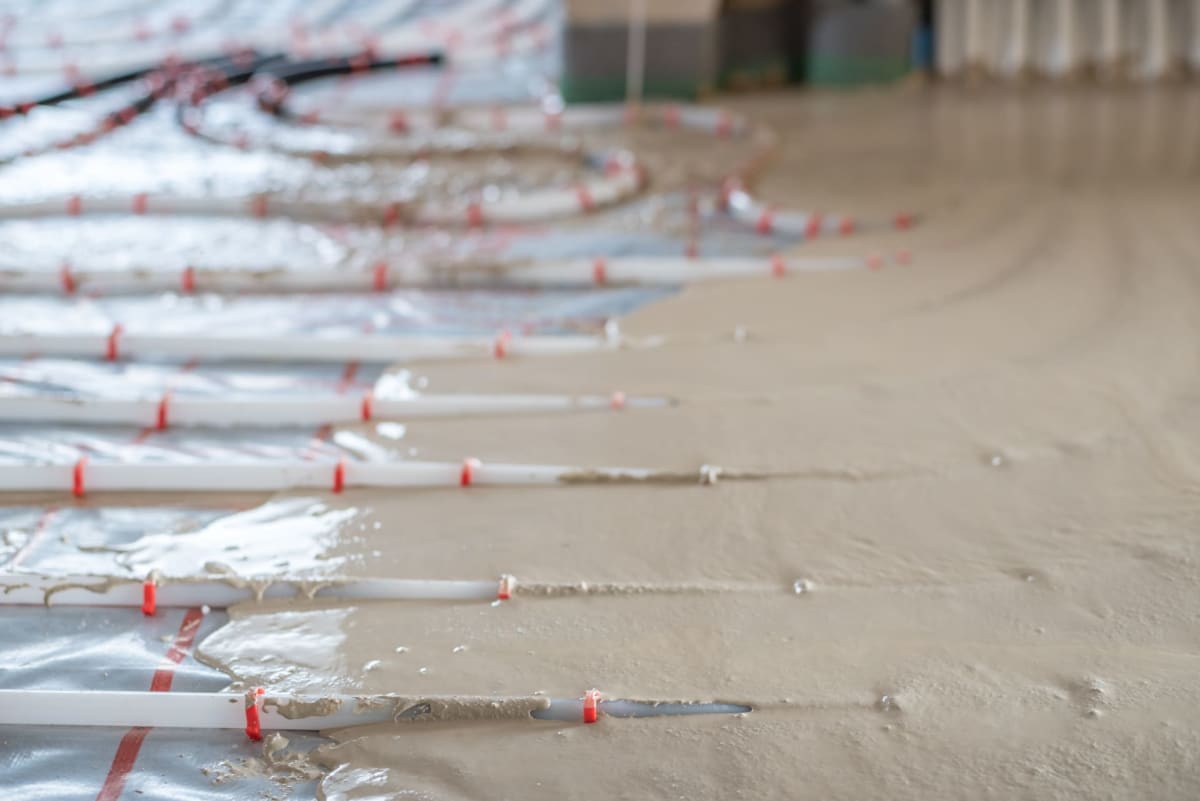 Fließestrich umschließt Fußbodenheizungsrohre auf Tackersystem – hohlraumfreie Rohrüberdeckung beim Einbau