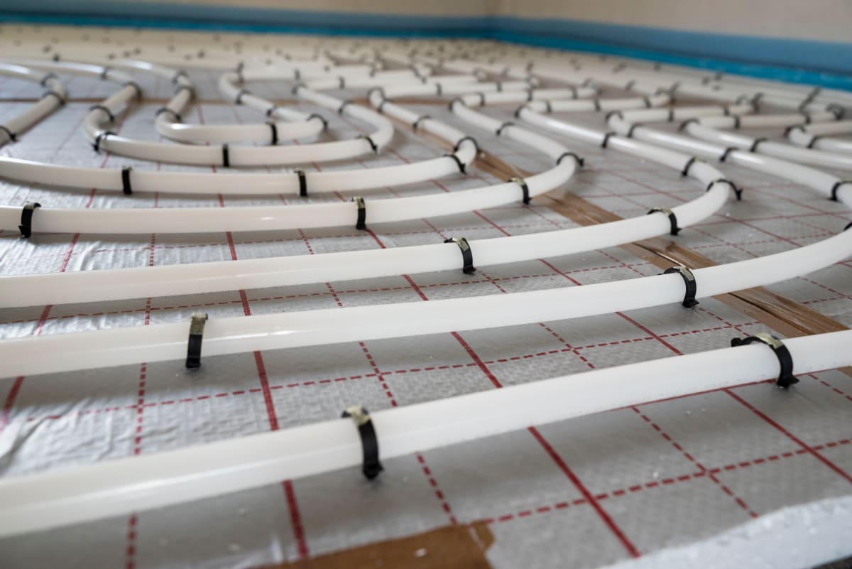 Tackersystem Fußbodenheizung: PE-Xa Heizrohre mit Tackernadeln auf Dämmplatte fixiert