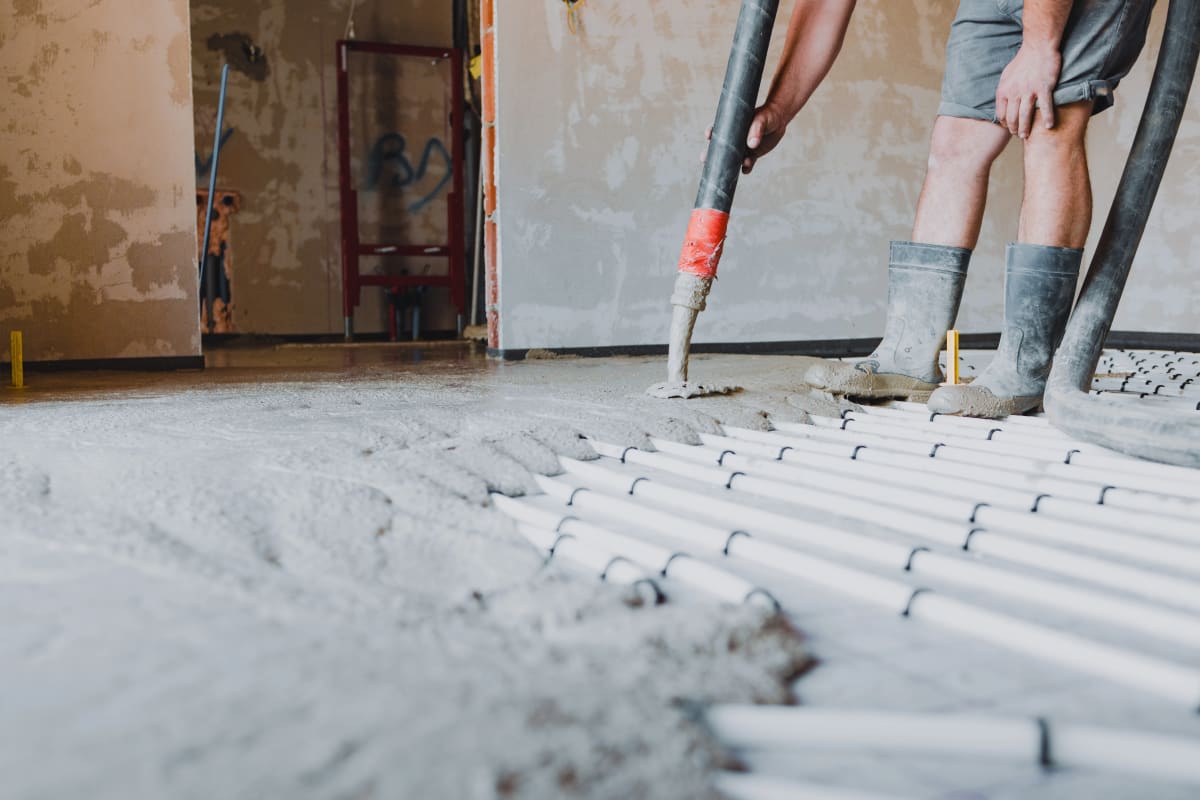 Estrichleger pumpt Fließestrich auf Tackerplatte mit Fußbodenheizung