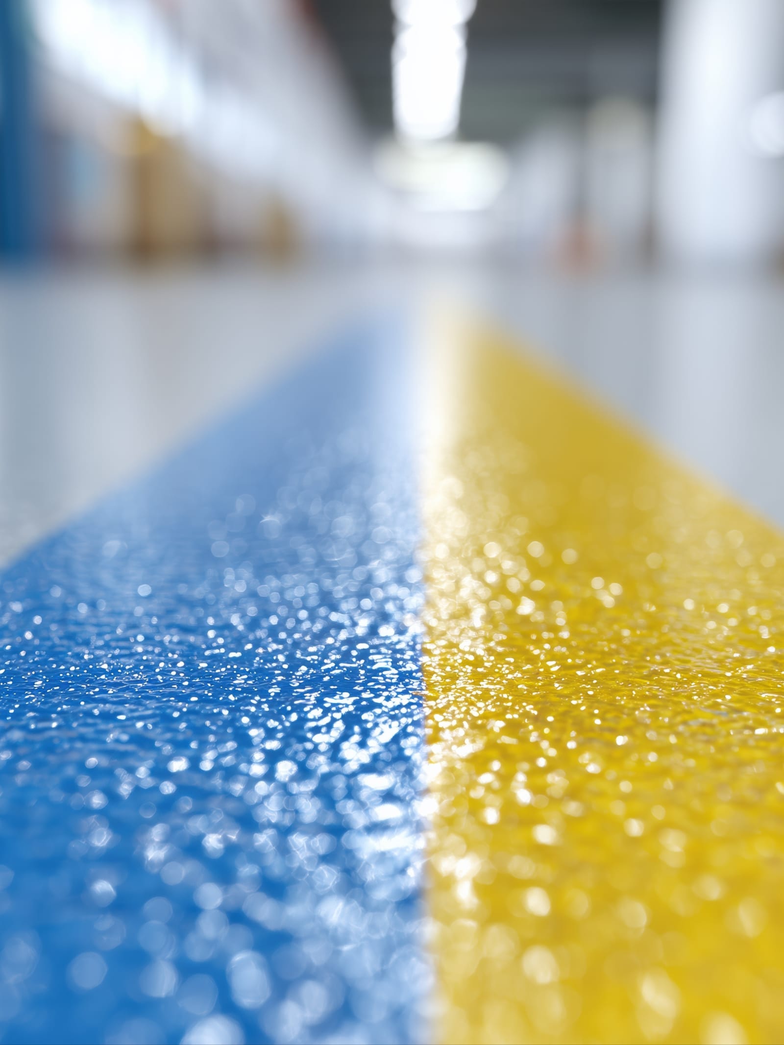 Epoxidharz-Bodenbeschichtung mit blau-gelber Sicherheitsmarkierung auf Industrieboden – fugenlose Kunstharzbeschichtung
