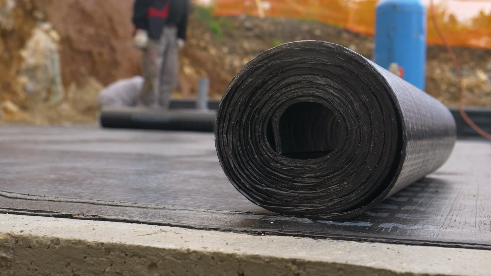 Handwerker verschweißt Bitumenbahn auf einer Betonbodenplatte