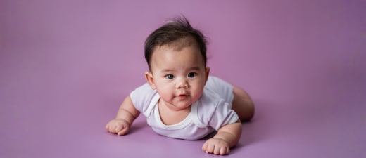 Baby liggend op de buik met paarse achtergrond