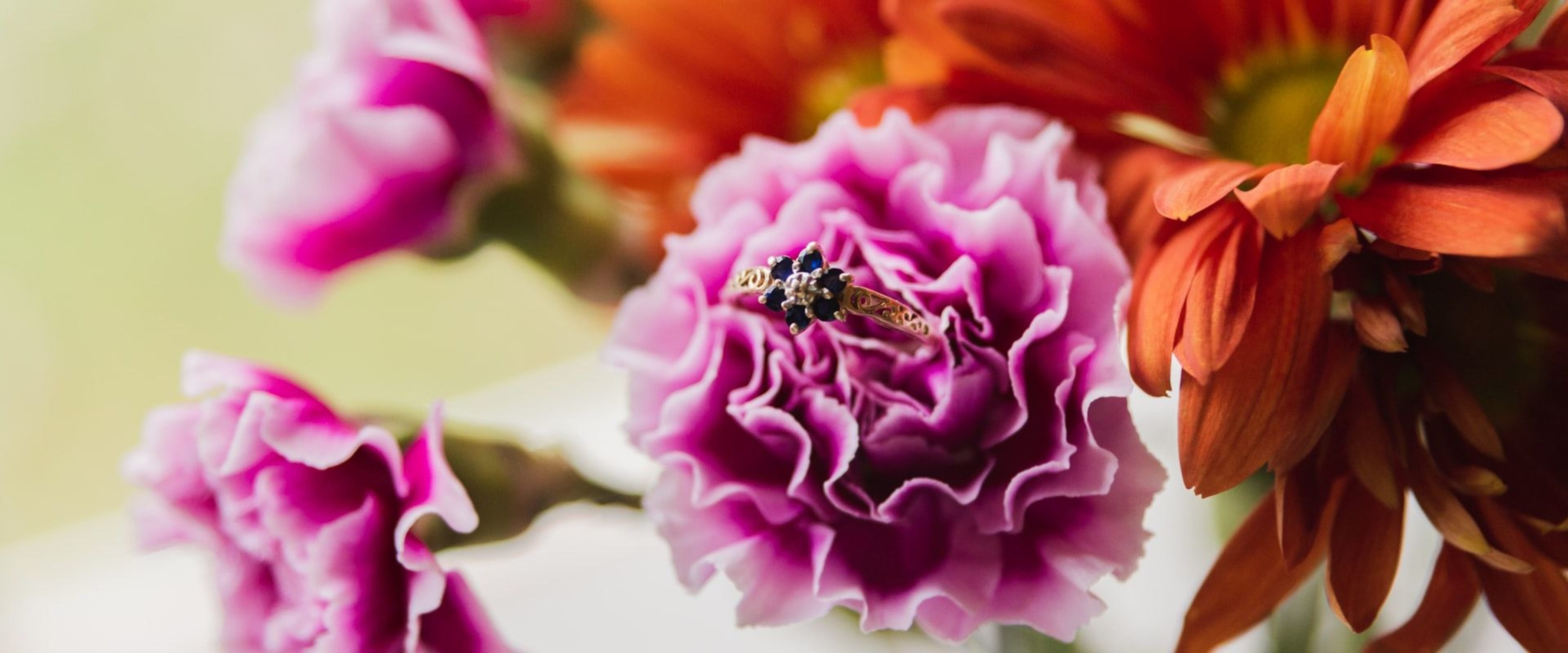 A deep blue sapphire held in dark tweezers against a neutral ground