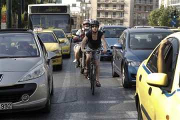 Elena Koniaraki rides her bicycle between cars at a central street in Athens