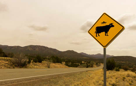 Cow Alien Abduction Road Sign along the Turqoise Trail, Route 66 Scenic Byway, in springtime between Santa Fe and Albuquerque, New Mexico.