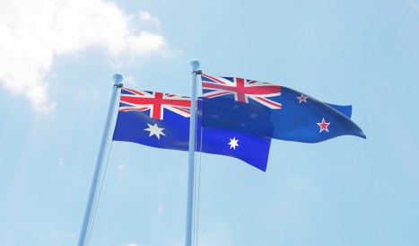 New Zealand and Australia, two flags waving against blue sky