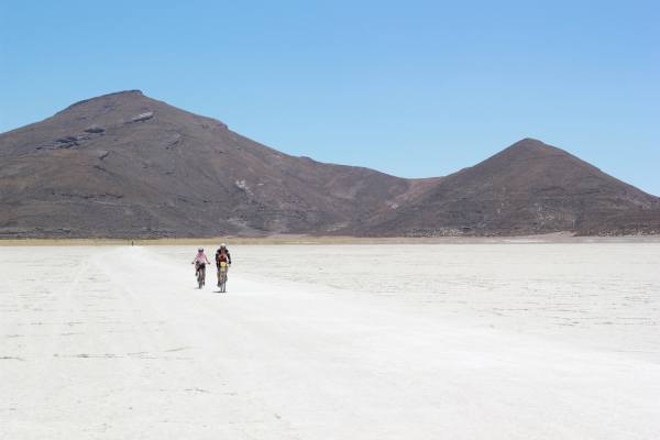 Kathy and Jean ride the salt flats with Tunapa Volcano in the background