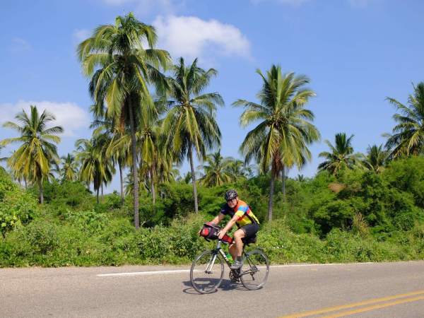 Wayne rides past palm trees in mainland Mexico