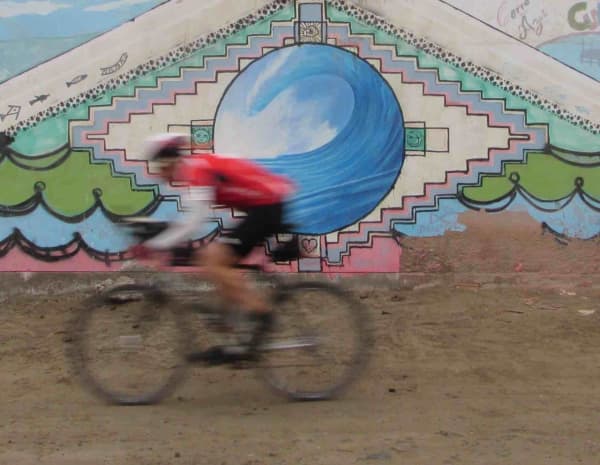 Chris speeds past a mural in Cerro Azul