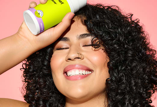 woman with curly hair holding SuperCream bottle
