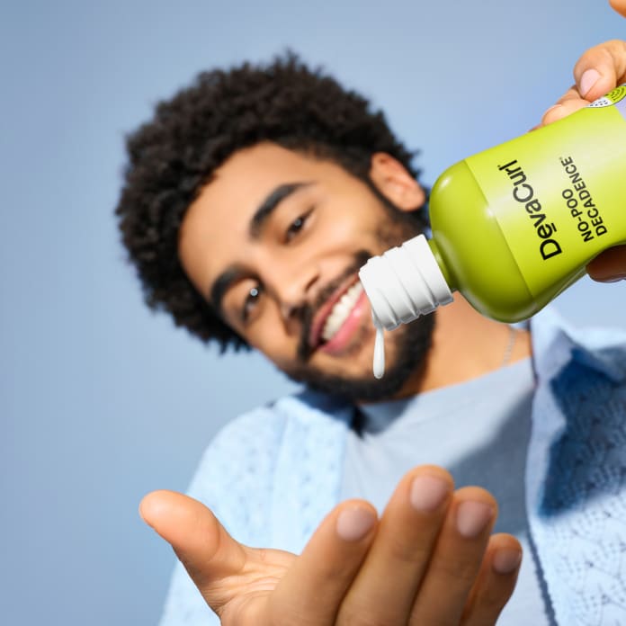 smiling man with curl hair squeezing No-Poo Decadence into hand