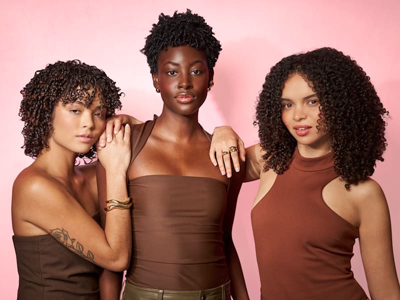 model with curly hair holding Quench'n bottle