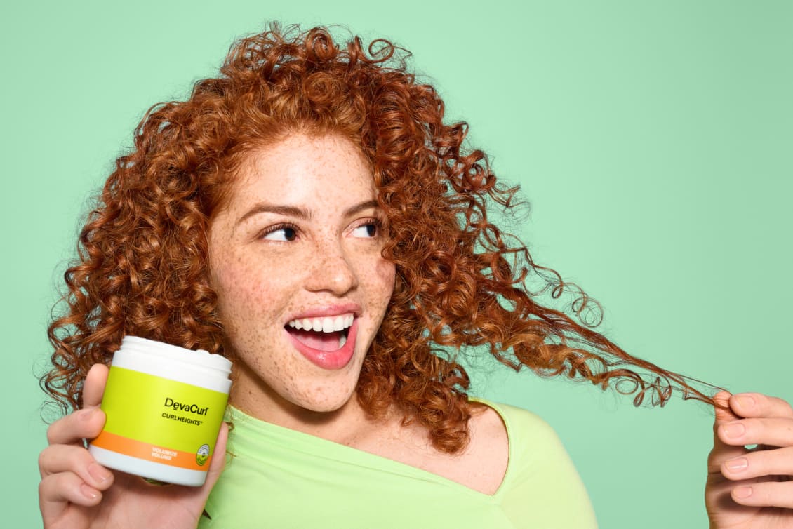 Woman with red curly hair holding CurlHeights Cream